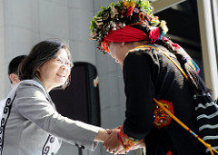 President Tsai shakes hands with an indigenous individual wearing her black traditional cloth.