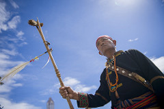 An indigenous elder stands under the blue sky.