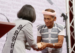 總統與原住民族代表夏本．嘎那恩在講臺上握手